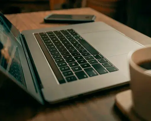 ordinateur portable posé sur une table, avec une tasse de café à côté